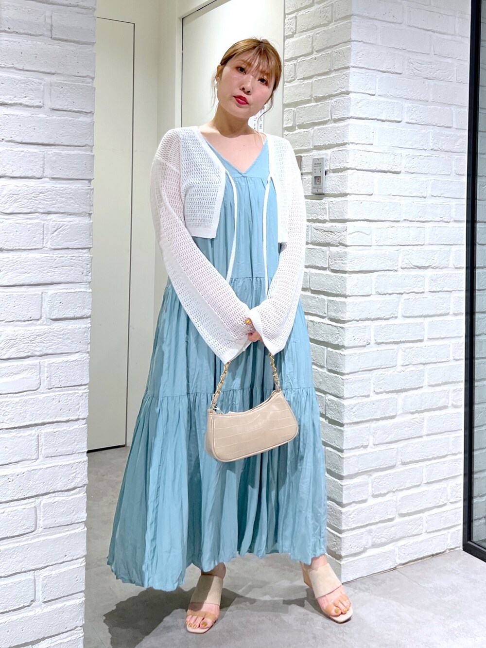 ホワイト系のカーディガン/ボレロ、グリーン系のワンピース、グレー系のサンダルを着用したレディースの夏コーディネートの2枚目の写真