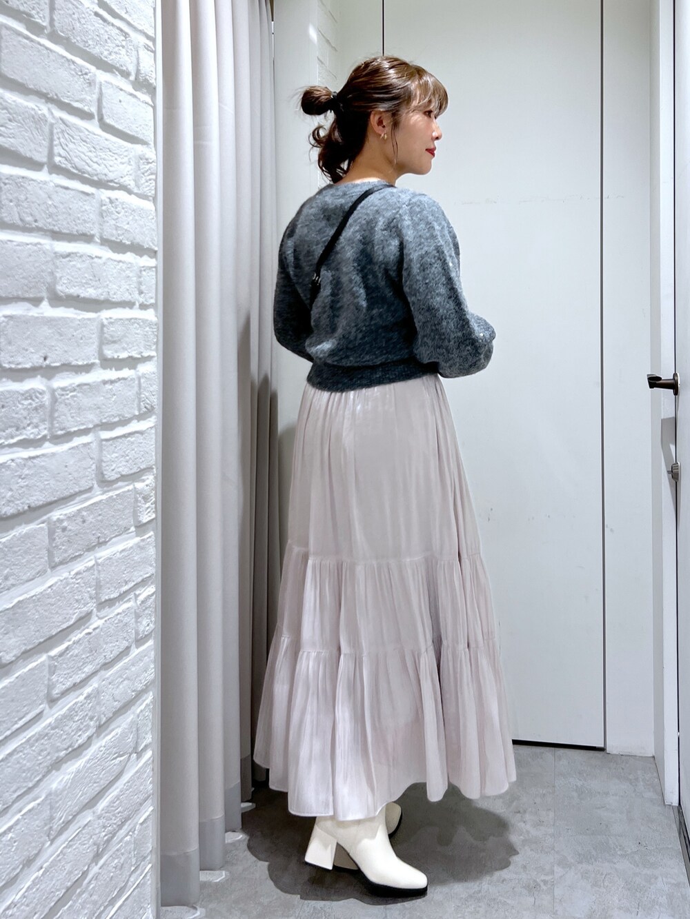 ホワイト系のスカート、グレー系のニット/セーター、ブラック系のショルダーバッグを着用したレディースの冬コーディネートの4枚目の写真