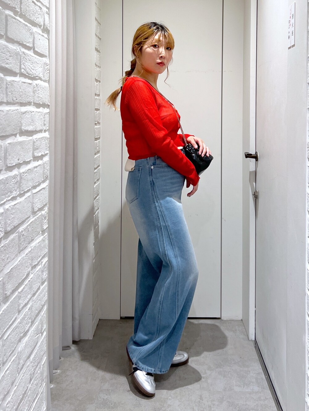 ブルー系のデニムパンツ、レッド系のカーディガン/ボレロ、ブラック系のショルダーバッグを着用したレディースの夏コーディネートの2枚目の写真