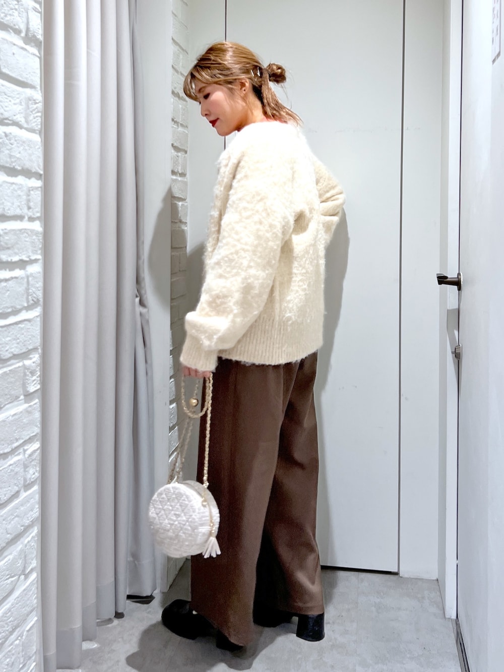 ブラウン系のスラックス、ベージュ系のニット/セーター、オレンジ系のニット/セーターを着用したレディースの秋コーディネートの3枚目の写真