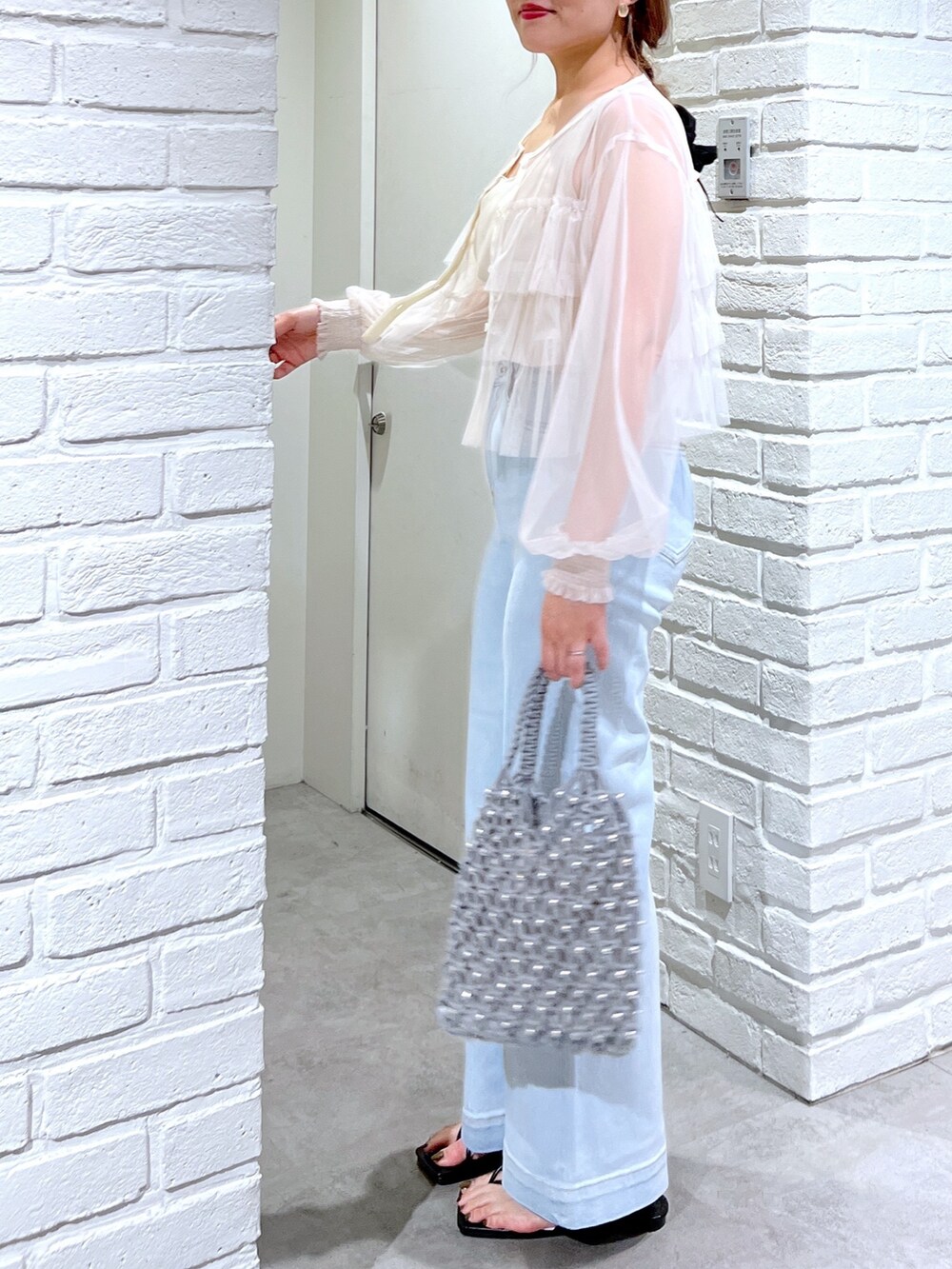 ブルー系のデニムパンツ、グリーン系のハンドバッグ、ホワイト系のシャツ/ブラウスを着用したレディースの夏コーディネートの5枚目の写真