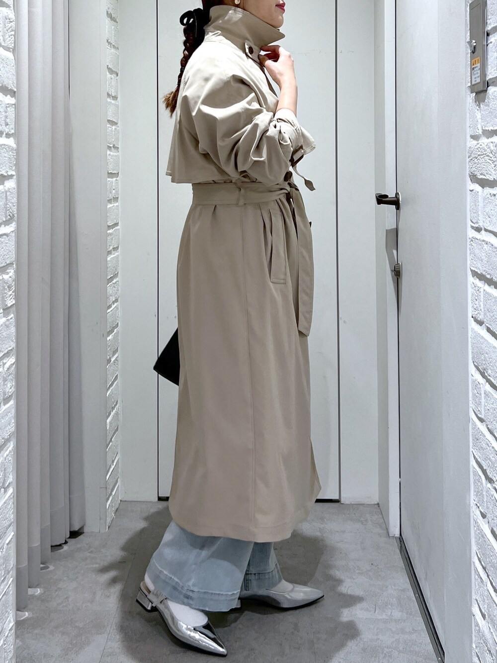 ベージュ系のトレンチコート、ブラック系のショルダーバッグ、ブルー系のデニムパンツを着用したレディースの春コーディネートの7枚目の写真