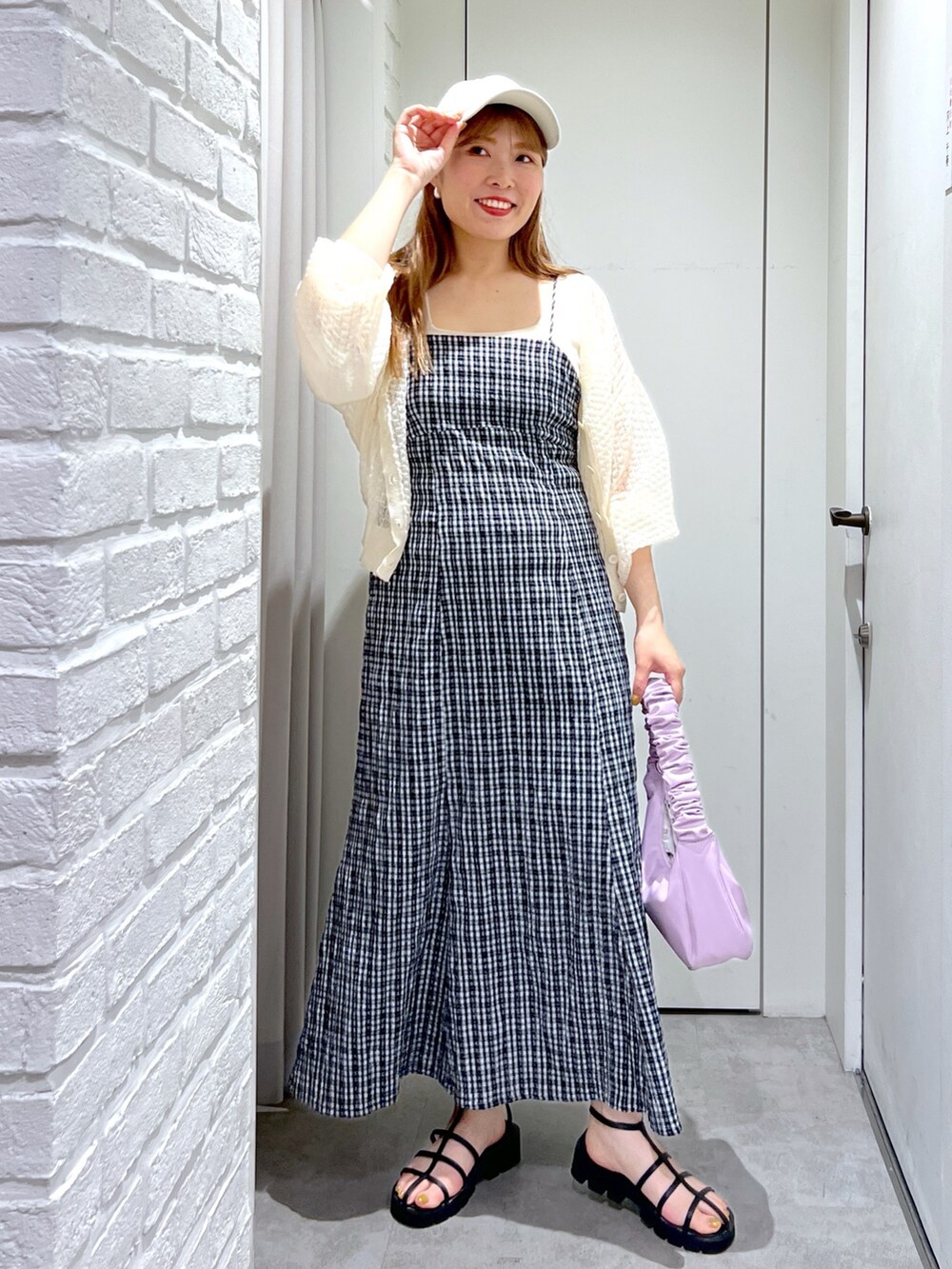 パープル系のハンドバッグ、ブラック系のサンダル、ホワイト系のカーディガン/ボレロを着用したレディースの夏コーディネートの2枚目の写真