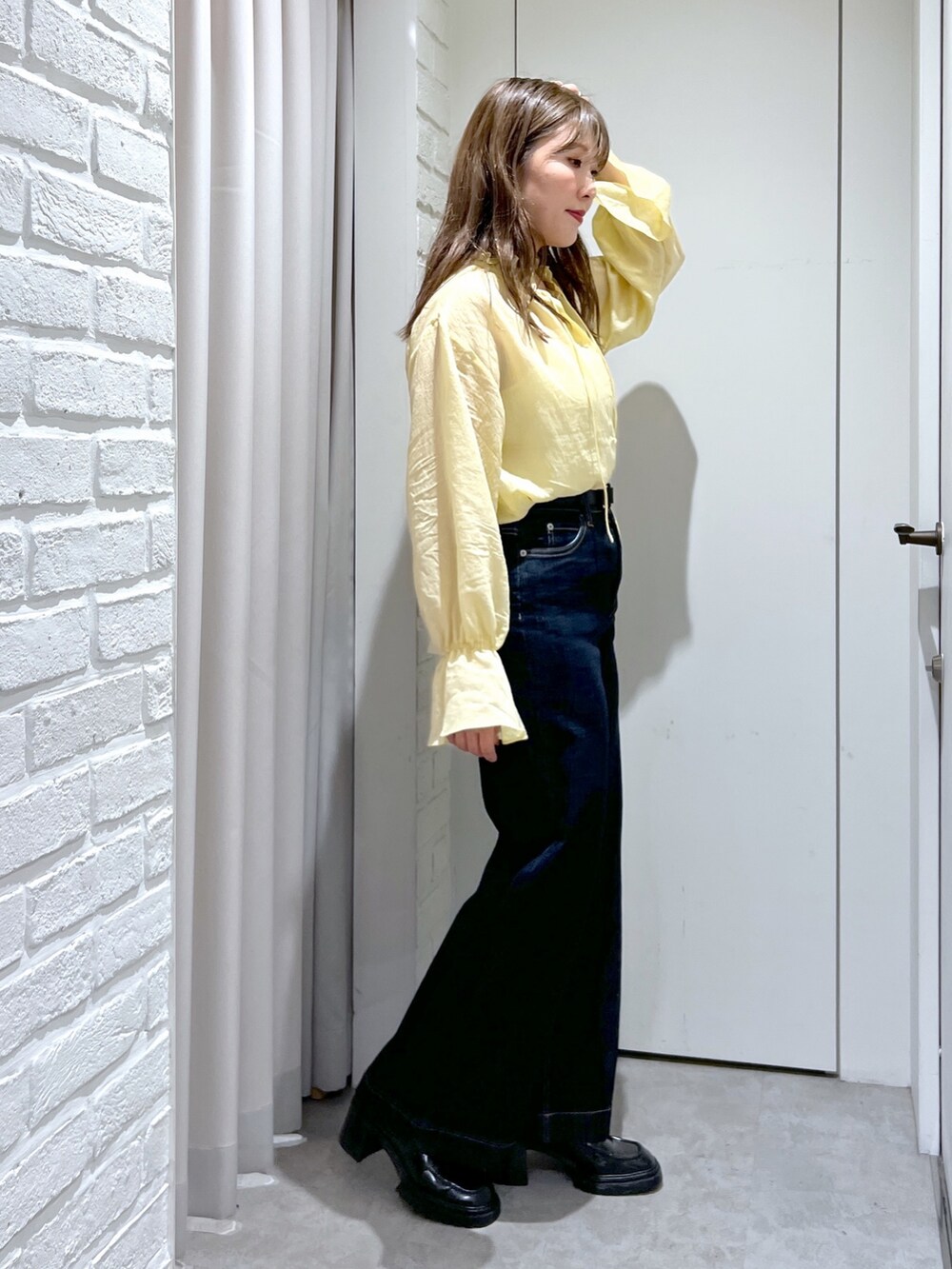 ブルー系のデニムパンツ、イエロー系のシャツ/ブラウス、ブラック系のショルダーバッグを着用したレディースの秋コーディネートの2枚目の写真