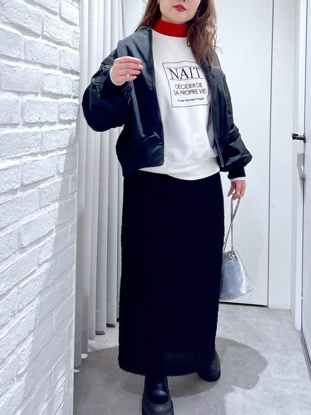 ブラック系のスカート、ホワイト系のスウェット、ブラック系のMA-1を着用したレディースの冬コーディネートの5枚目の写真