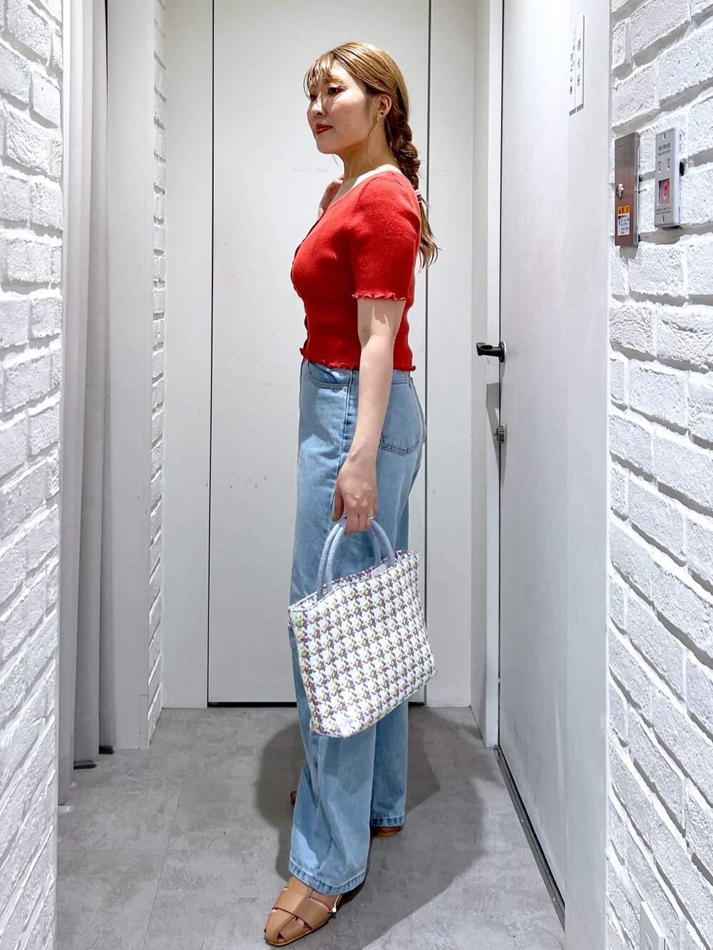 レッド系のニット/セーター、ブルー系のデニムパンツ、ベージュ系のスリッポンを着用したレディースの夏コーディネートの3枚目の写真