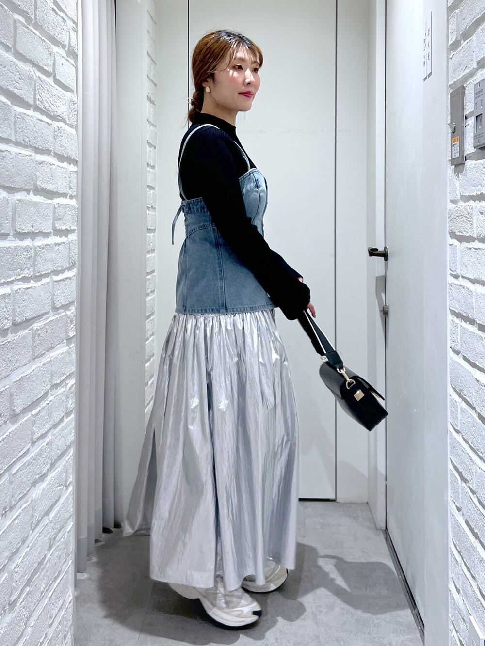 シルバー系のスカート、ブルー系のベスト、ブラック系のニット/セーターを着用したレディースの春コーディネートの3枚目の写真