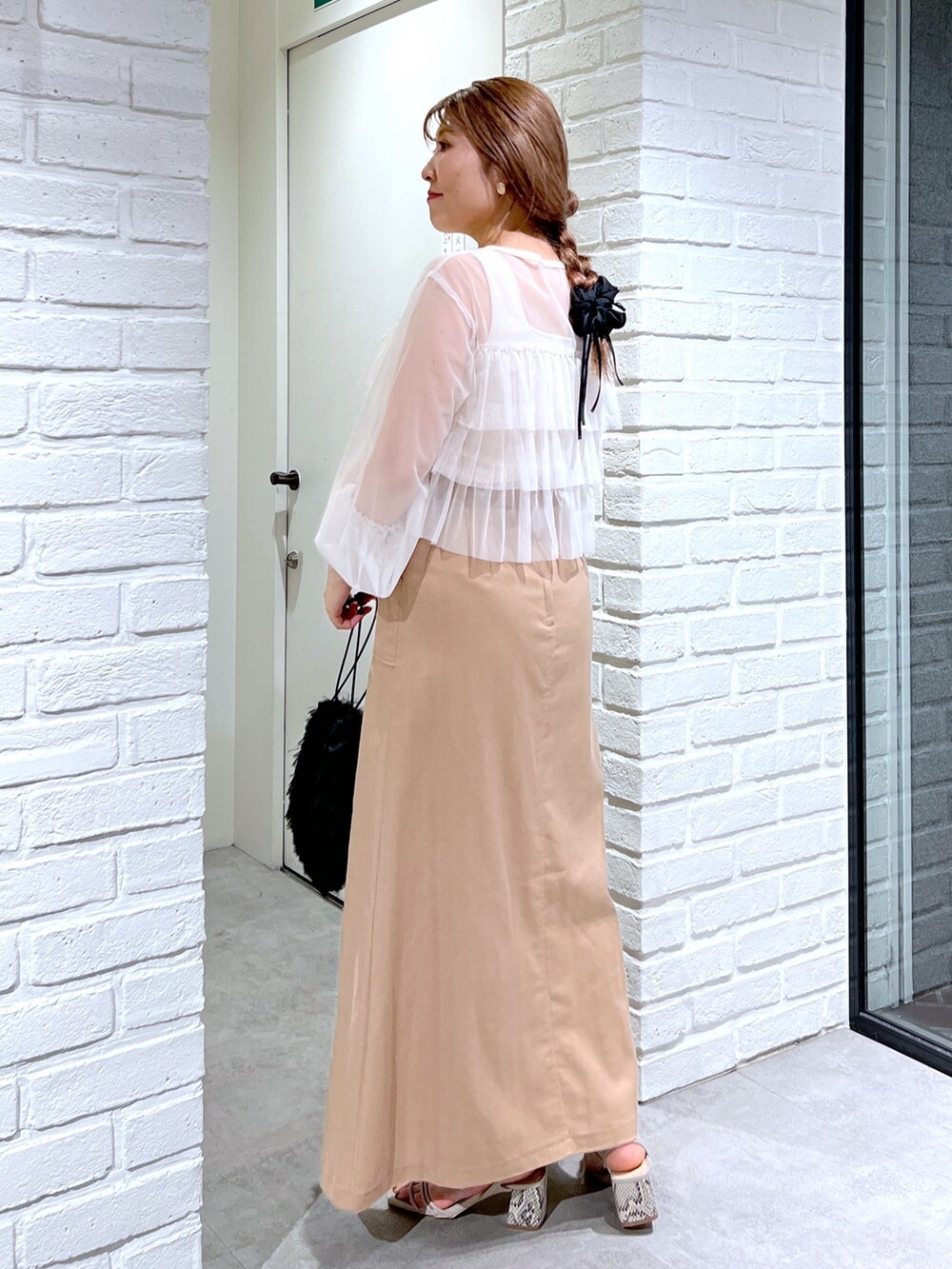 ブラウン系のスカート、ブラック系のハンドバッグ、グレー系のサンダルを着用したレディースの夏コーディネートの5枚目の写真