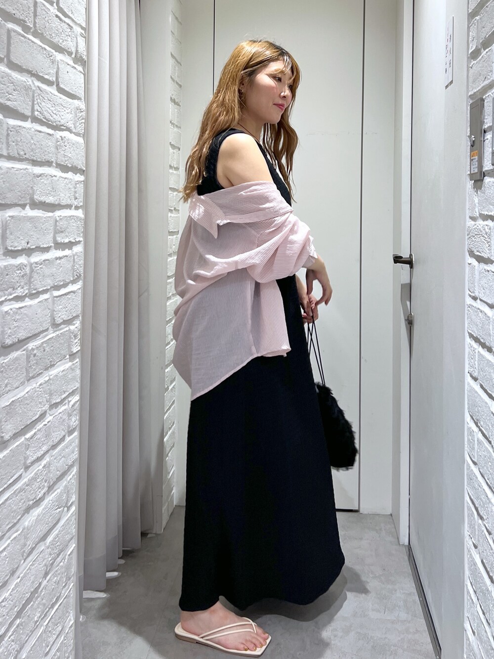 ブラック系のワンピース、ブラック系のハンドバッグ、ホワイト系のサンダルを着用したレディースの夏コーディネートの3枚目の写真