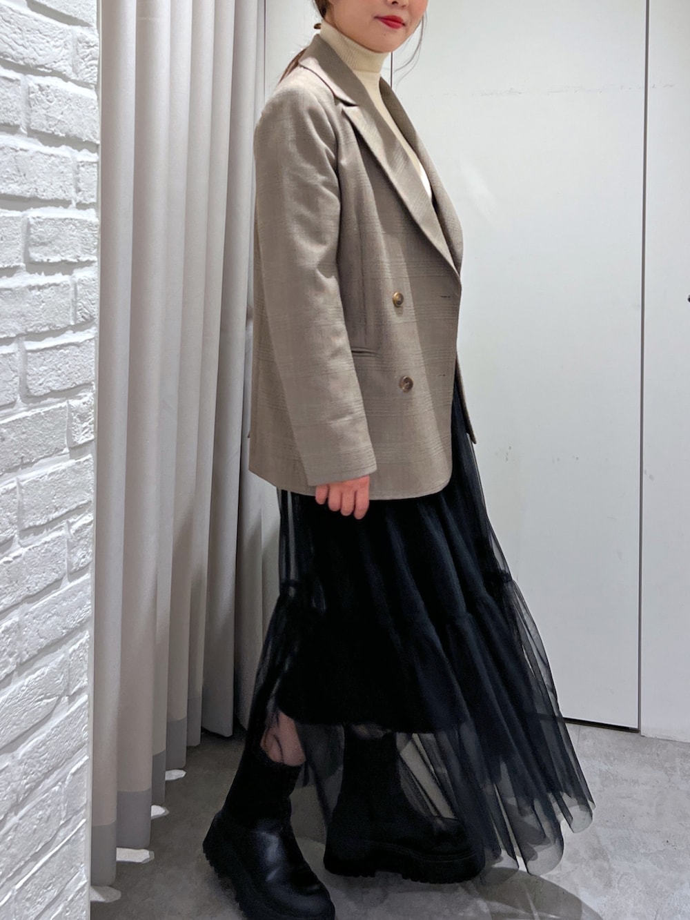 ブラウン系のテーラードジャケット、ホワイト系のニット/セーター、ブラック系のスカートを着用したレディースの秋コーディネートの3枚目の写真