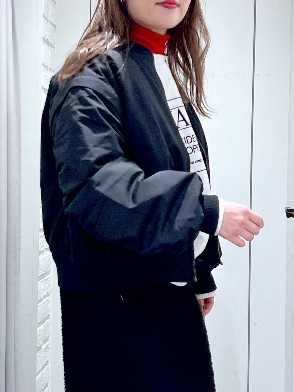 ブラック系のスカート、ホワイト系のスウェット、ブラック系のMA-1を着用したレディースの冬コーディネートの7枚目の写真