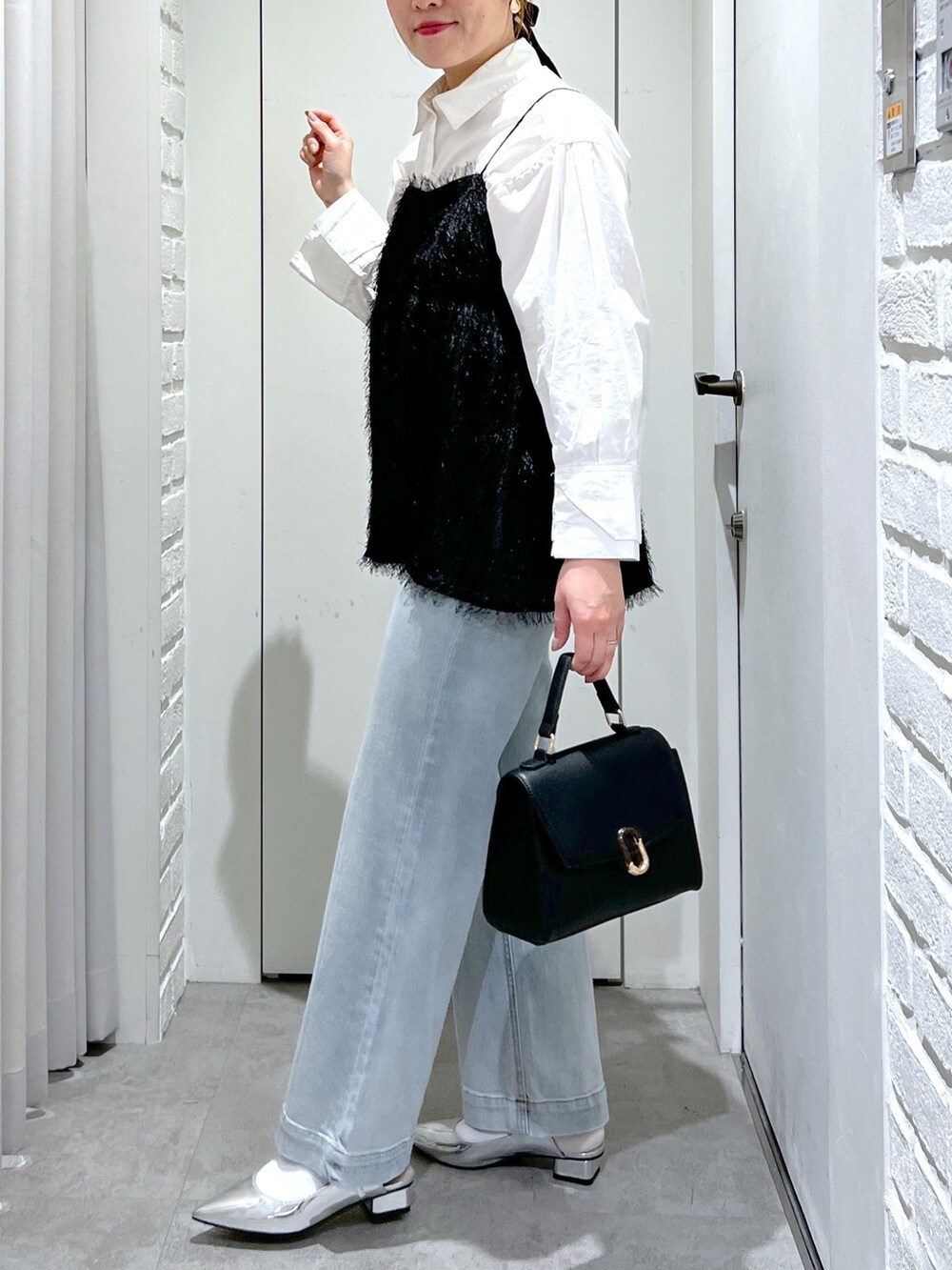 ブラック系のシャツ/ブラウス、ブルー系のデニムパンツ、シルバー系のパンプスを着用したレディースの冬コーディネートの7枚目の写真