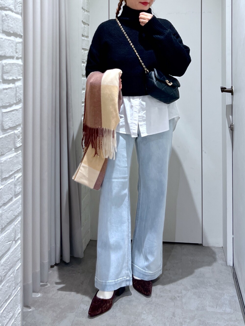 ブルー系のデニムパンツ、ブラック系のショルダーバッグ、ブラック系のニット/セーターを着用したレディースの冬コーディネートの5枚目の写真