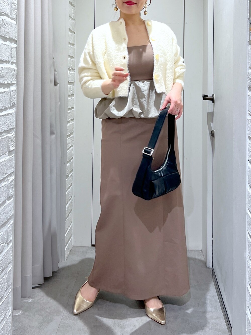 ブラウン系のワンピース、ブラック系のショルダーバッグ、ゴールド系のパンプスを着用したレディースの冬コーディネートの5枚目の写真