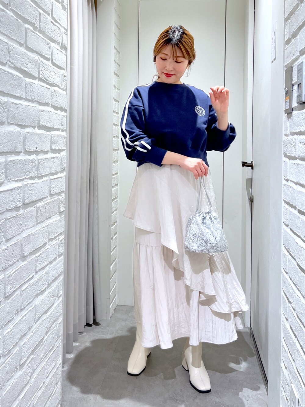 ホワイト系のスカート、ホワイト系のブーツ、シルバー系のハンドバッグを着用したレディースの春コーディネートの2枚目の写真