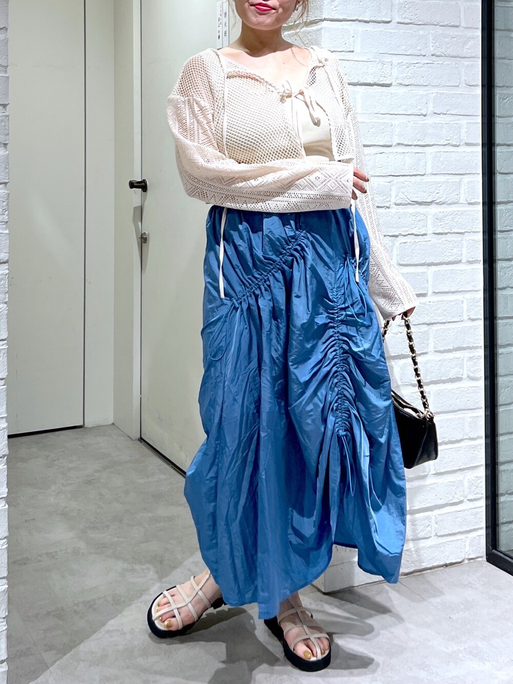 ブルー系のスカート、ホワイト系のカーディガン/ボレロ、ホワイト系のサンダルを着用したレディースの夏コーディネートの4枚目の写真