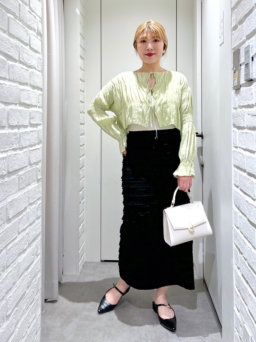 ブラック系のスカート、グリーン系のシャツ/ブラウス、ホワイト系のショルダーバッグを着用したレディースの春コーディネートの2枚目の写真