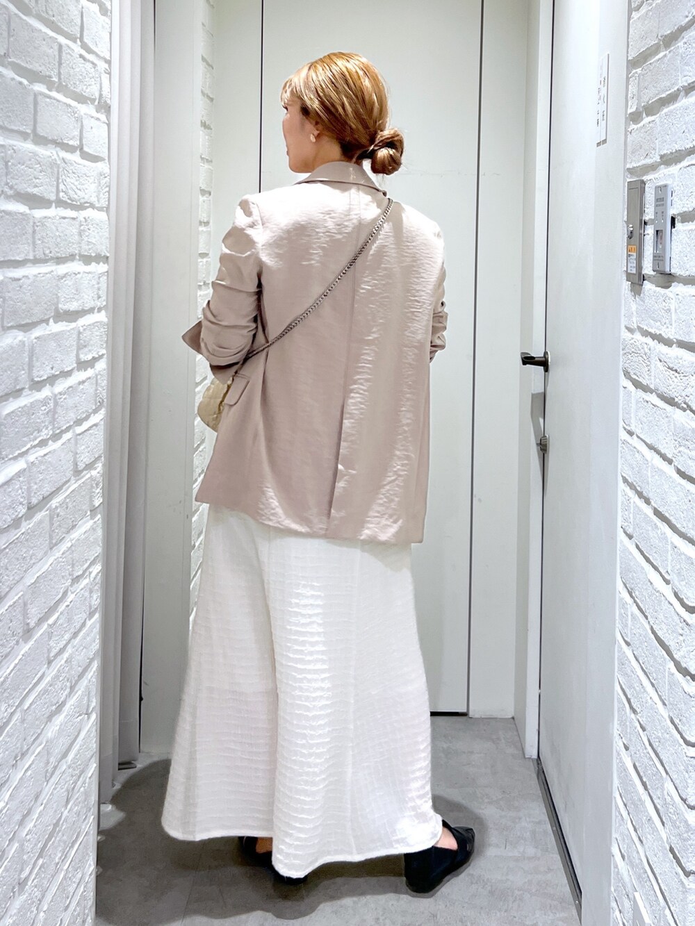 ホワイト系のワンピース、ゴールド系のショルダーバッグ、ブラック系のスリッポンを着用したレディースの春コーディネートの5枚目の写真