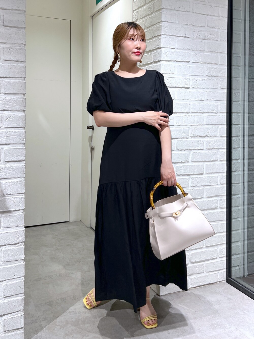 ホワイト系のショルダーバッグ、ブラック系のワンピース、イエロー系のサンダルを着用したレディースの夏コーディネートの2枚目の写真