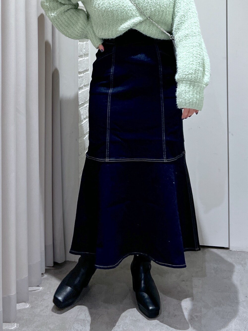 ブルー系のスカート、グリーン系のニット/セーター、シルバー系のショルダーバッグを着用したレディースの冬コーディネートの5枚目の写真