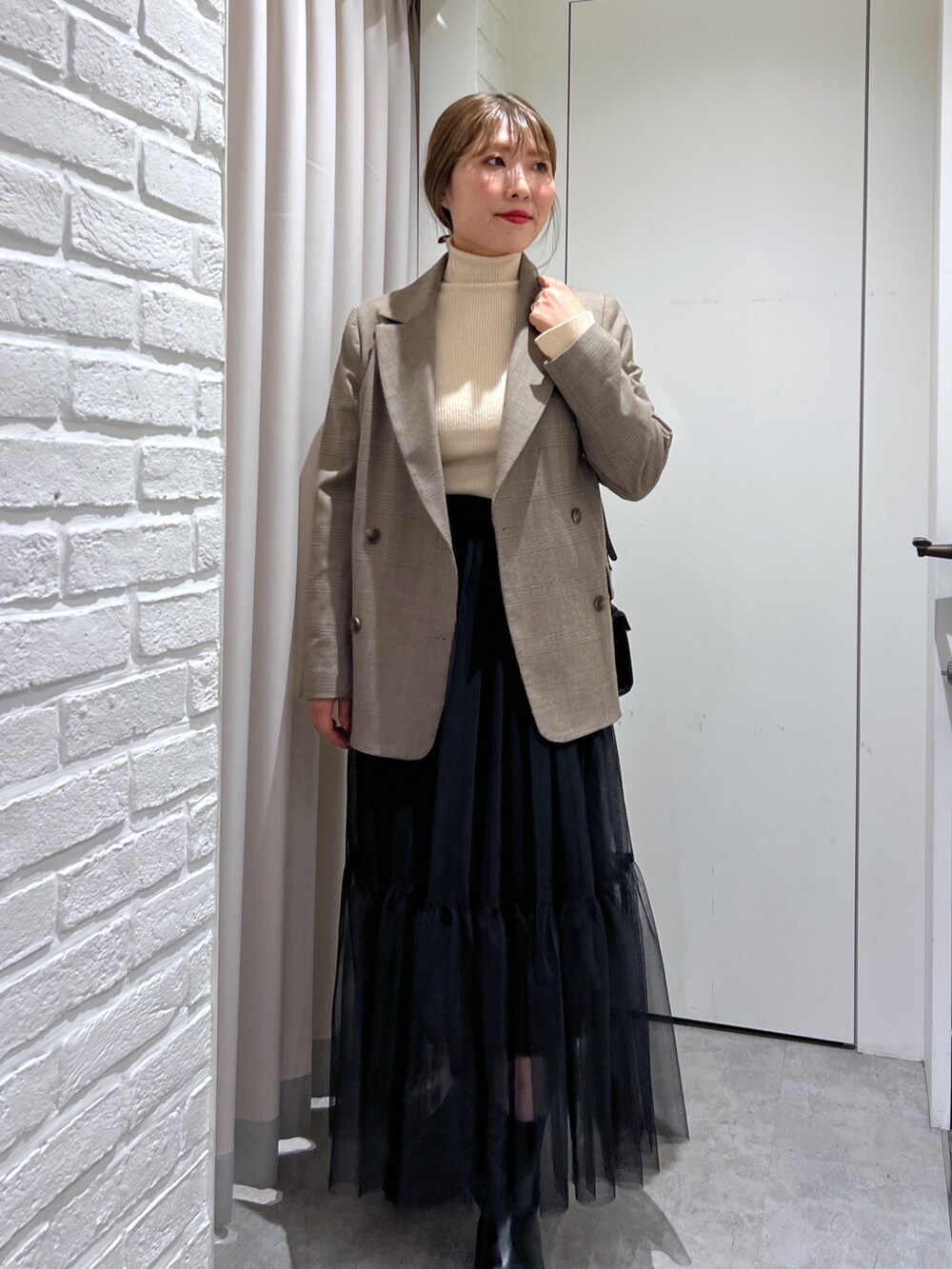ブラウン系のテーラードジャケット、ホワイト系のニット/セーター、ブラック系のスカートを着用したレディースの秋コーディネートの4枚目の写真