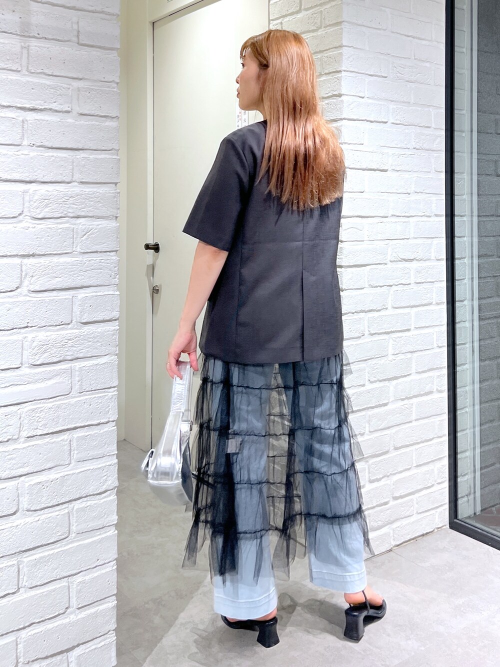 グレー系のノーカラージャケット、ブラック系のスカート、ブルー系のデニムパンツを着用したレディースの夏コーディネートの4枚目の写真