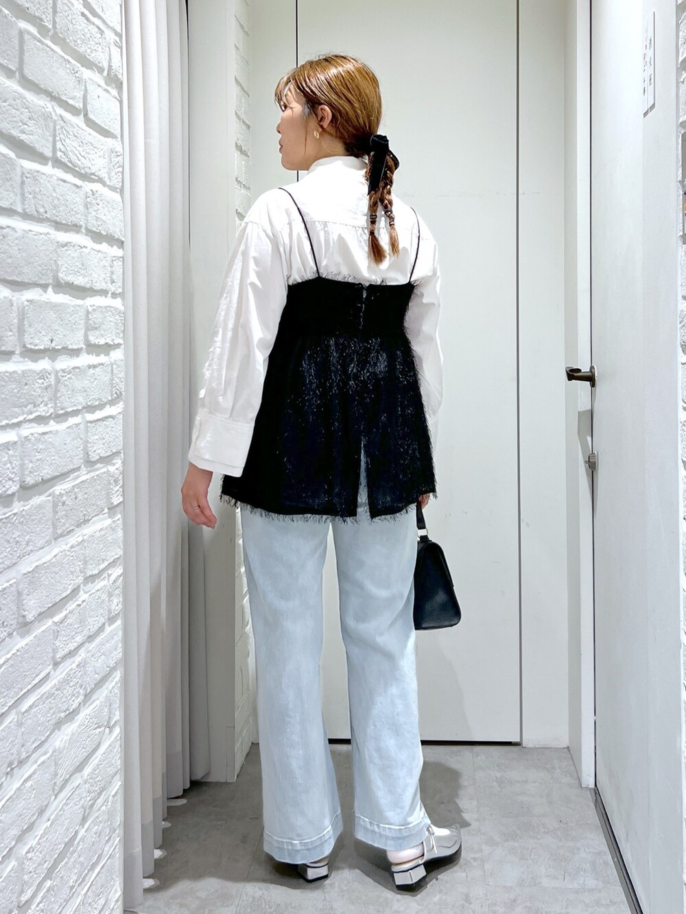 ブラック系のシャツ/ブラウス、ブルー系のデニムパンツ、シルバー系のパンプスを着用したレディースの冬コーディネートの4枚目の写真