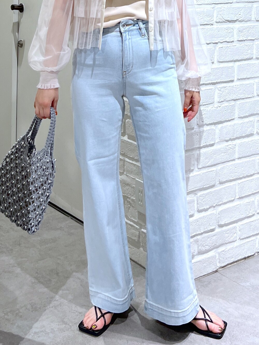 ブルー系のデニムパンツ、グリーン系のハンドバッグ、ホワイト系のシャツ/ブラウスを着用したレディースの夏コーディネートの7枚目の写真