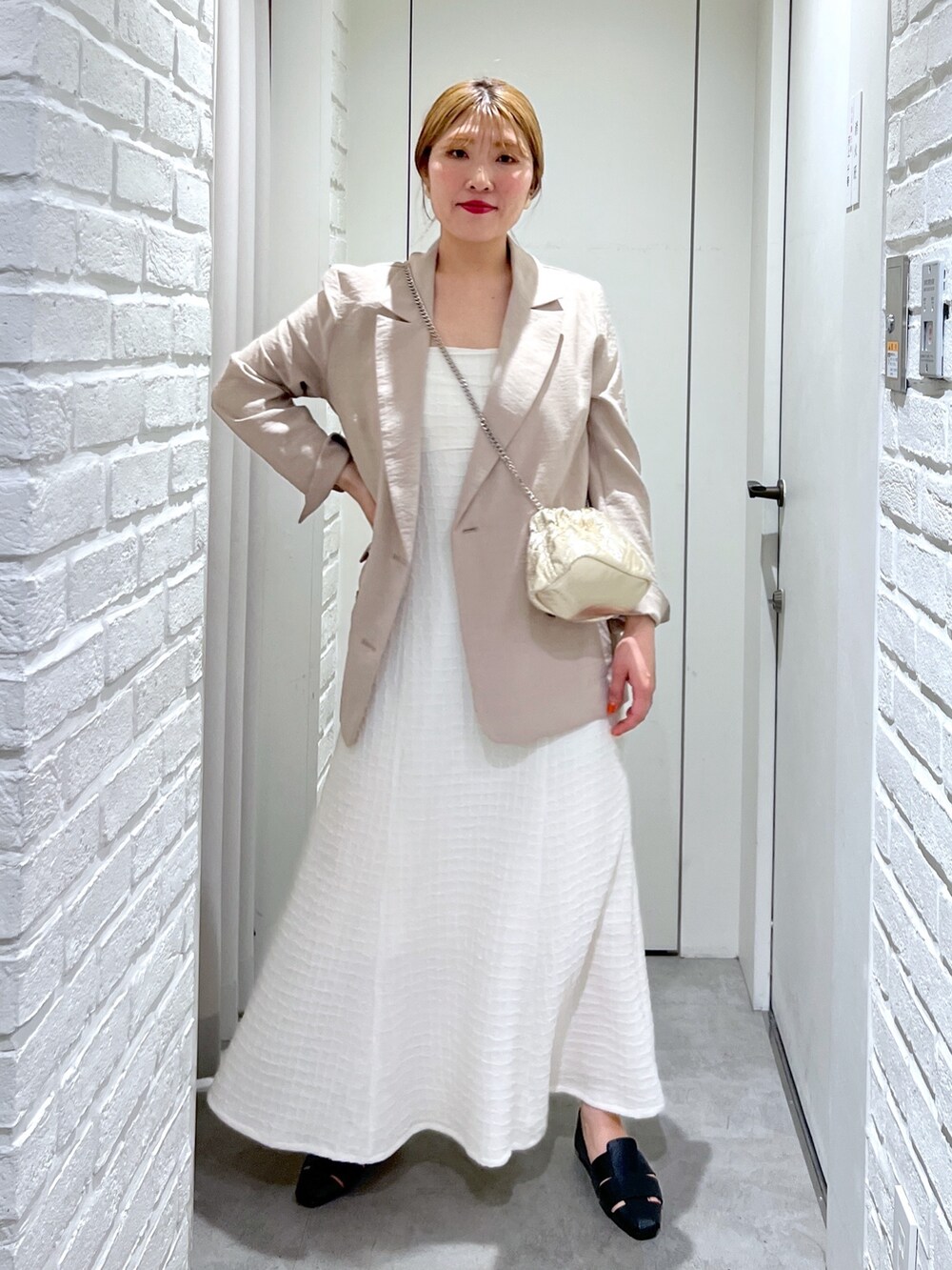 ホワイト系のワンピース、ゴールド系のショルダーバッグ、ブラック系のスリッポンを着用したレディースの春コーディネートの2枚目の写真