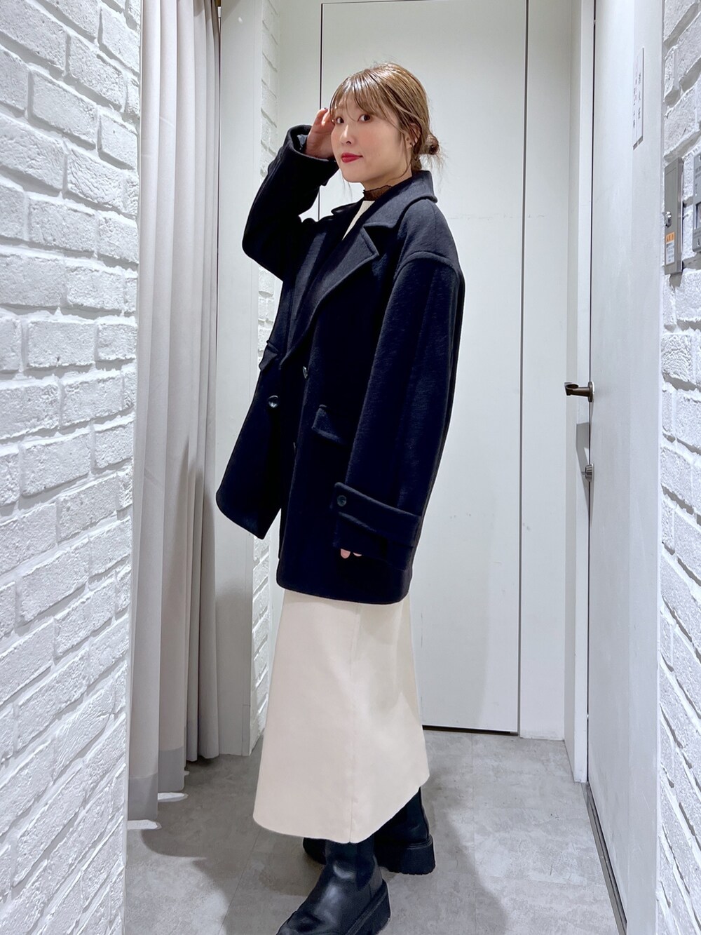 ブラック系のピーコート、ホワイト系のワンピース、ブラック系のTシャツ/カットソーを着用したレディースの冬コーディネートの2枚目の写真