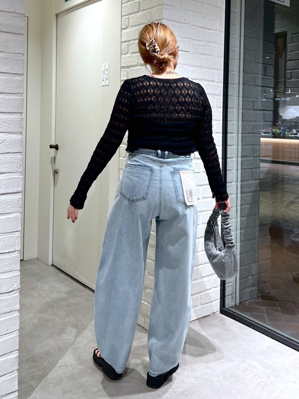 ブルー系のデニムパンツ、ブラック系のサンダル、シルバー系のハンドバッグを着用したレディースの夏コーディネートの4枚目の写真