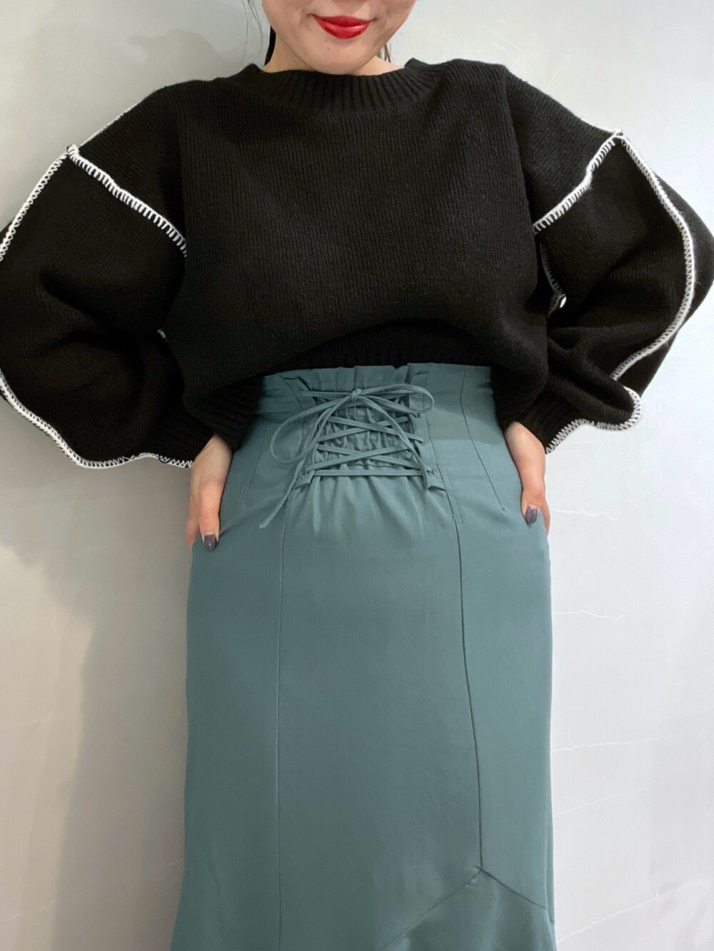 グリーン系のスカート、ブラック系のニット/セーター、ホワイト系のショルダーバッグを着用したレディースの冬コーディネートの5枚目の写真