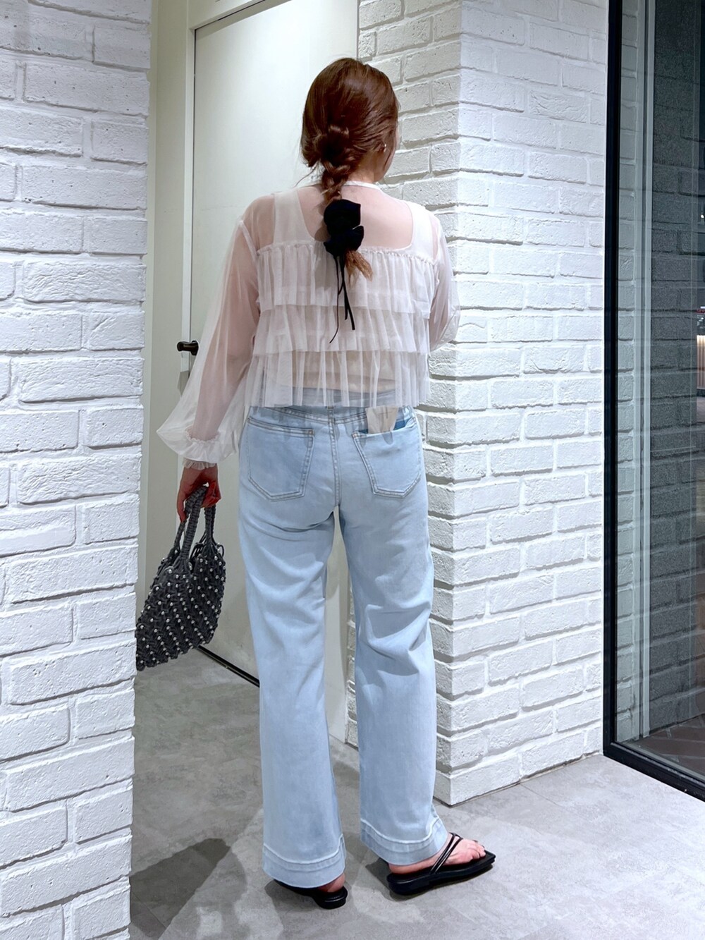 ブルー系のデニムパンツ、グリーン系のハンドバッグ、ホワイト系のシャツ/ブラウスを着用したレディースの夏コーディネートの3枚目の写真