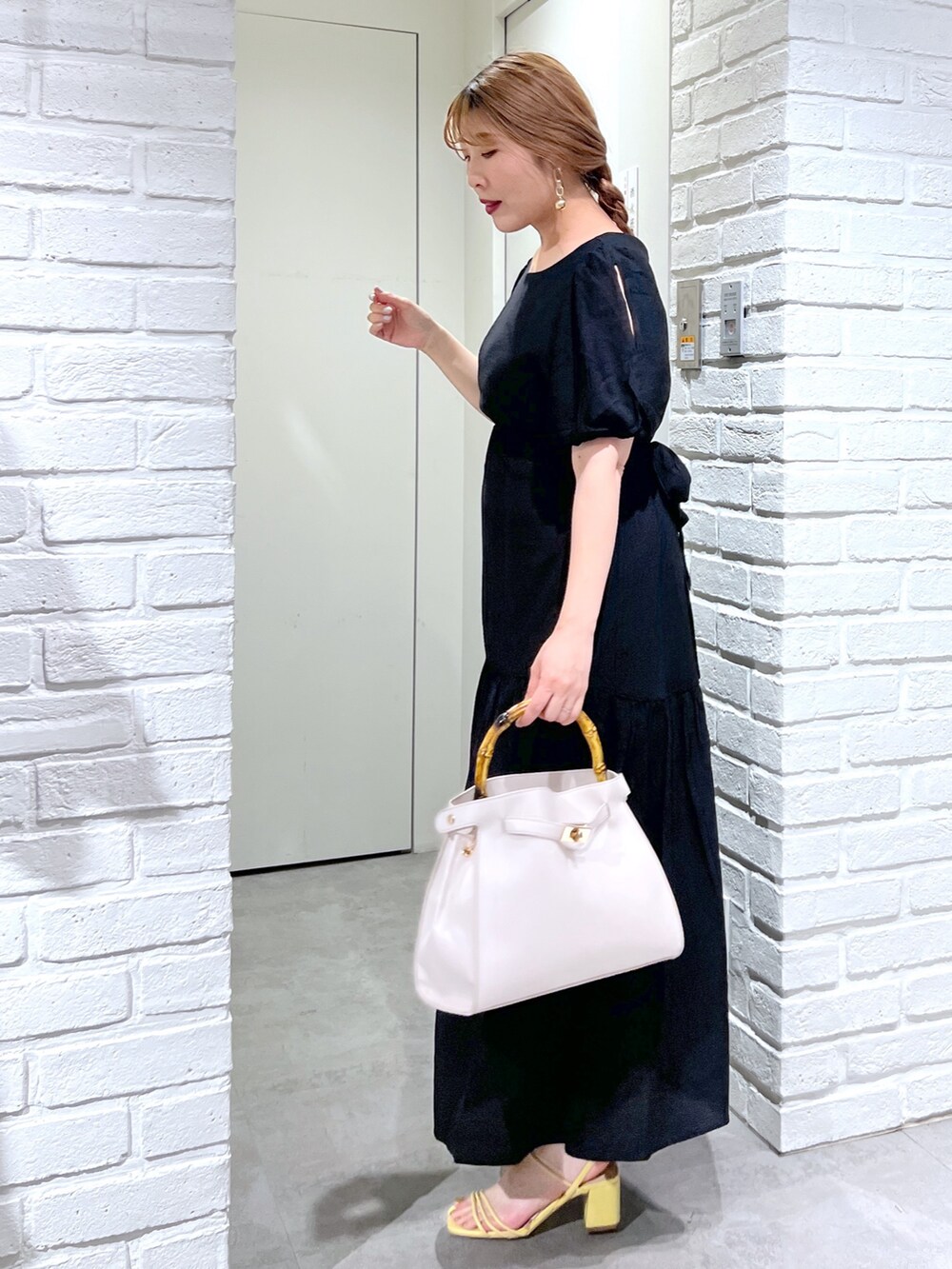 ホワイト系のショルダーバッグ、ブラック系のワンピース、イエロー系のサンダルを着用したレディースの夏コーディネートの5枚目の写真
