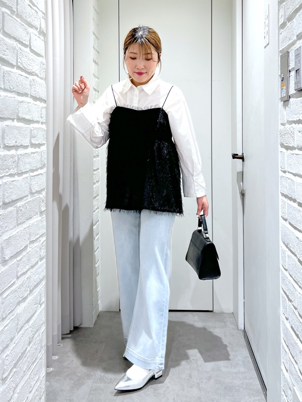 ブラック系のシャツ/ブラウス、ブルー系のデニムパンツ、シルバー系のパンプスを着用したレディースの冬コーディネートの2枚目の写真