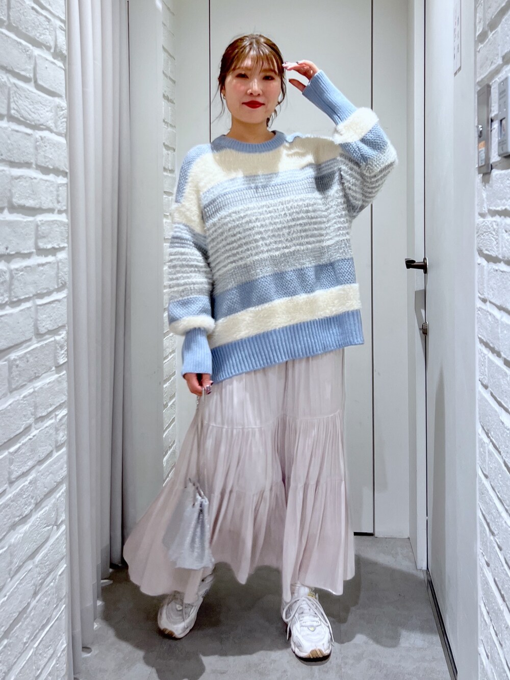 ブルー系のニット/セーター、ホワイト系のスカート、シルバー系のショルダーバッグを着用したレディースの冬コーディネートの4枚目の写真