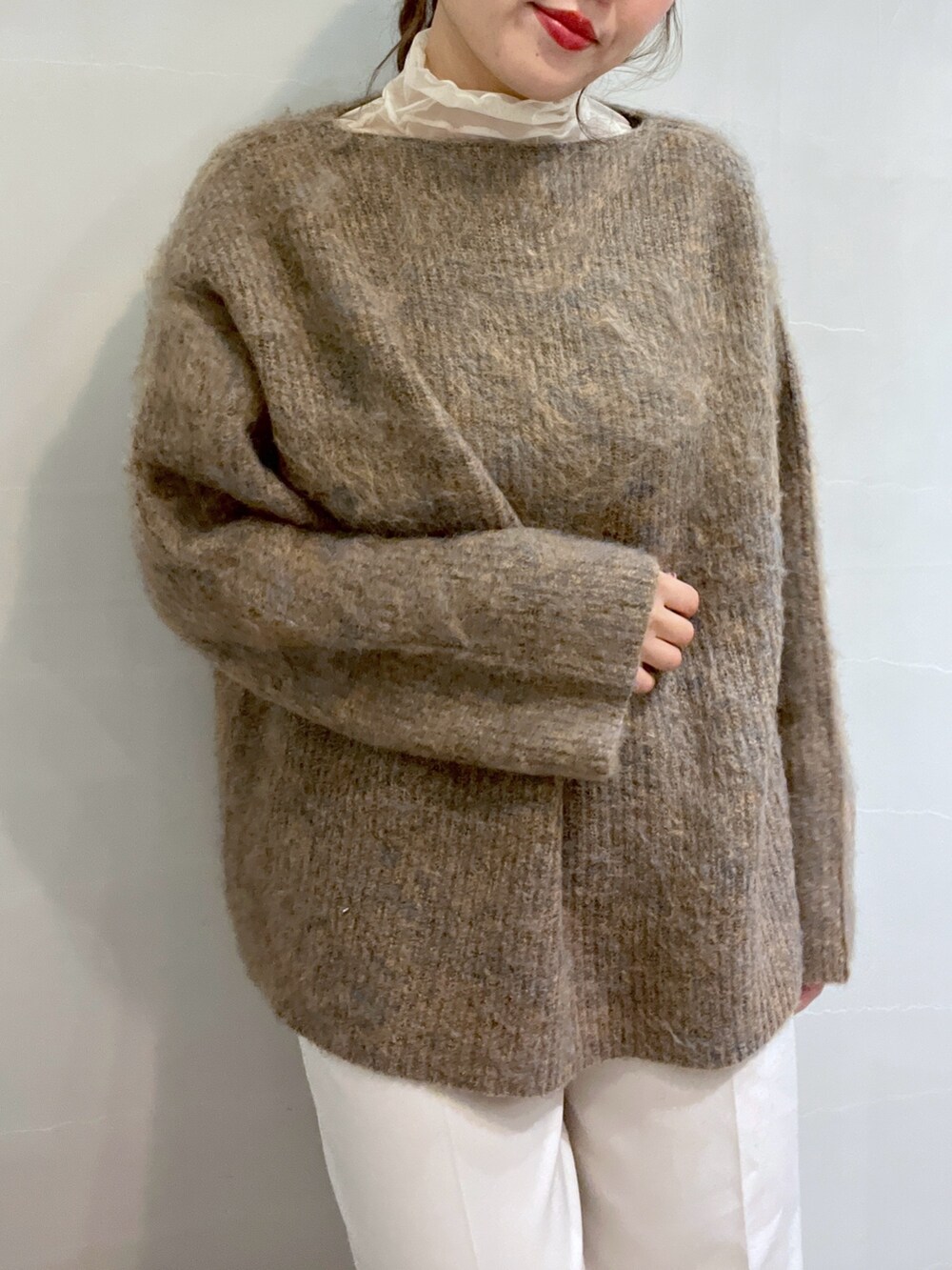 ベージュ系のニット/セーター、ホワイト系のスラックス、ホワイト系のショルダーバッグを着用したレディースの冬コーディネートの6枚目の写真