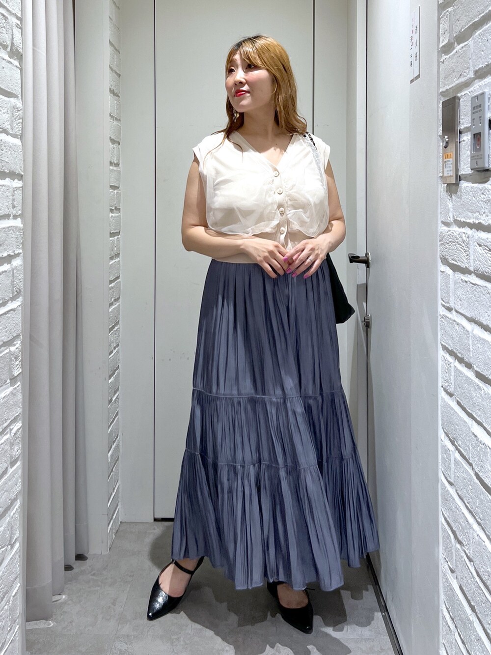 ブルー系のスカート、ホワイト系のベスト、ブラック系のパンプスを着用したレディースの夏コーディネートの8枚目の写真