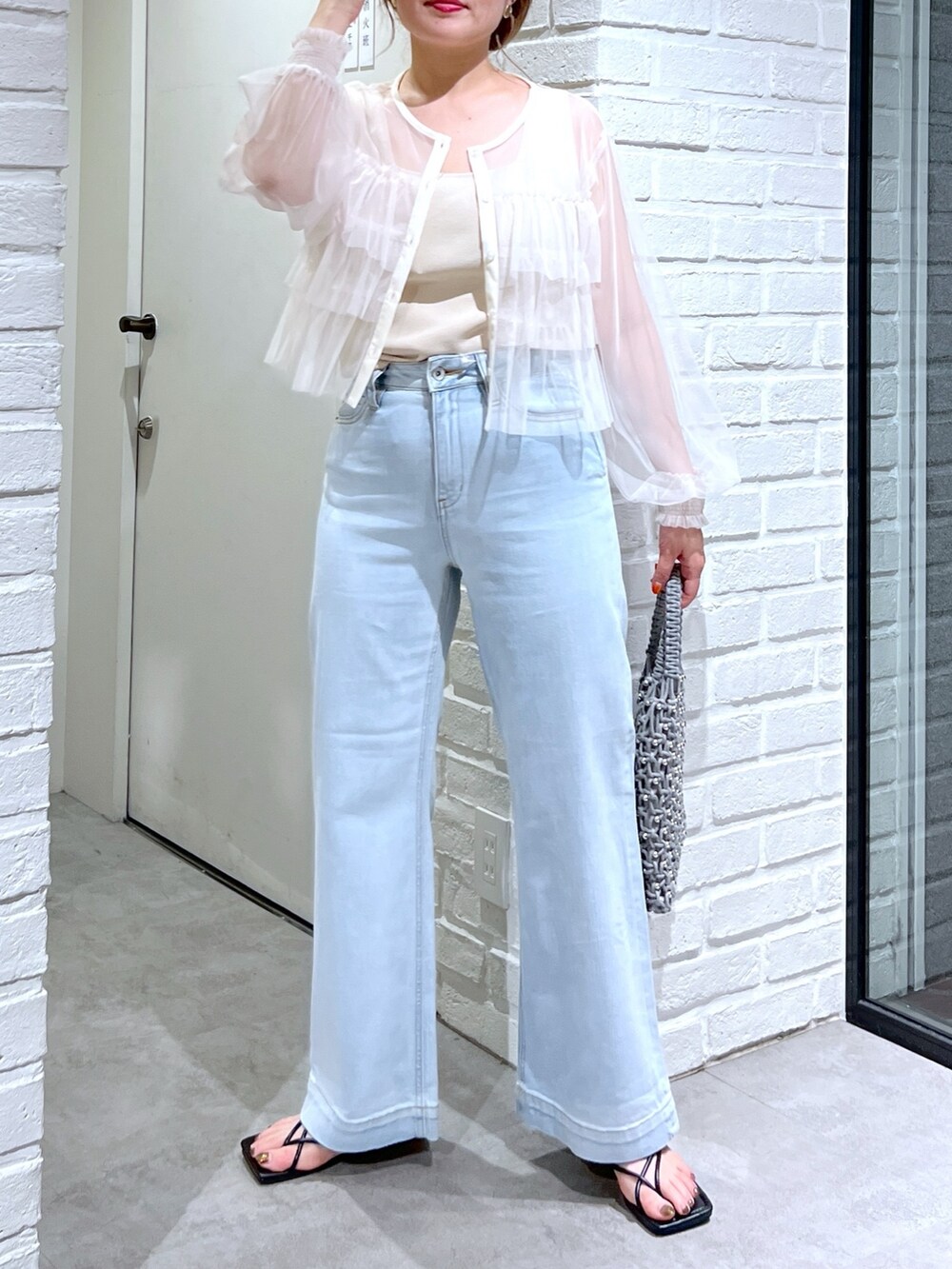 ブルー系のデニムパンツ、グリーン系のハンドバッグ、ホワイト系のシャツ/ブラウスを着用したレディースの夏コーディネートの4枚目の写真