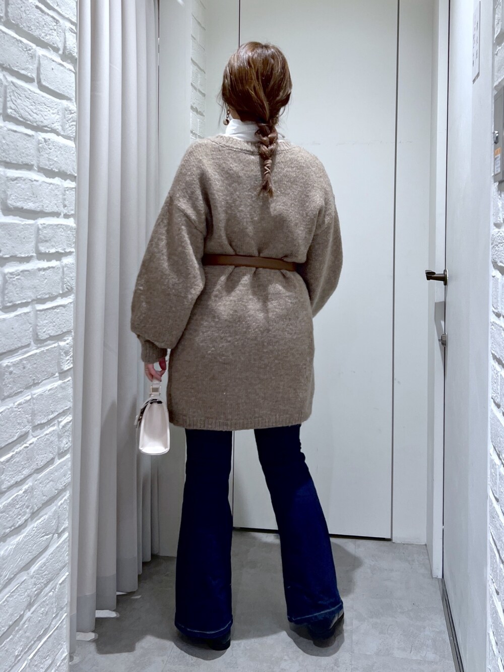 ブラウン系のワンピース、ホワイト系のショルダーバッグ、ブラック系のローファーを着用したレディースの冬コーディネートの4枚目の写真