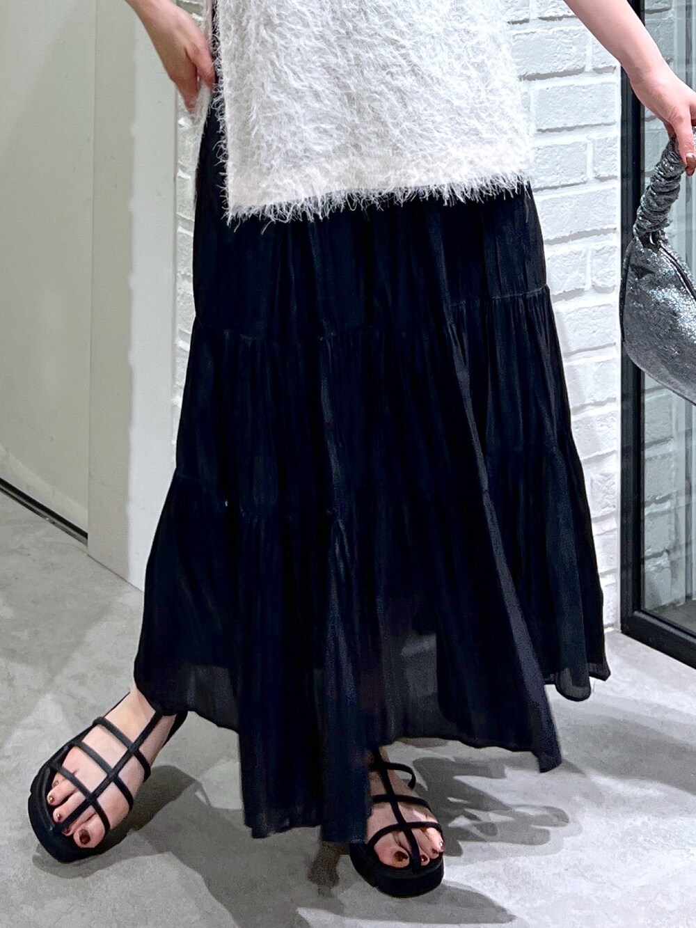 ホワイト系のシャツ/ブラウス、ブラック系のスカート、ブラック系のサンダルを着用したレディースの夏コーディネートの8枚目の写真