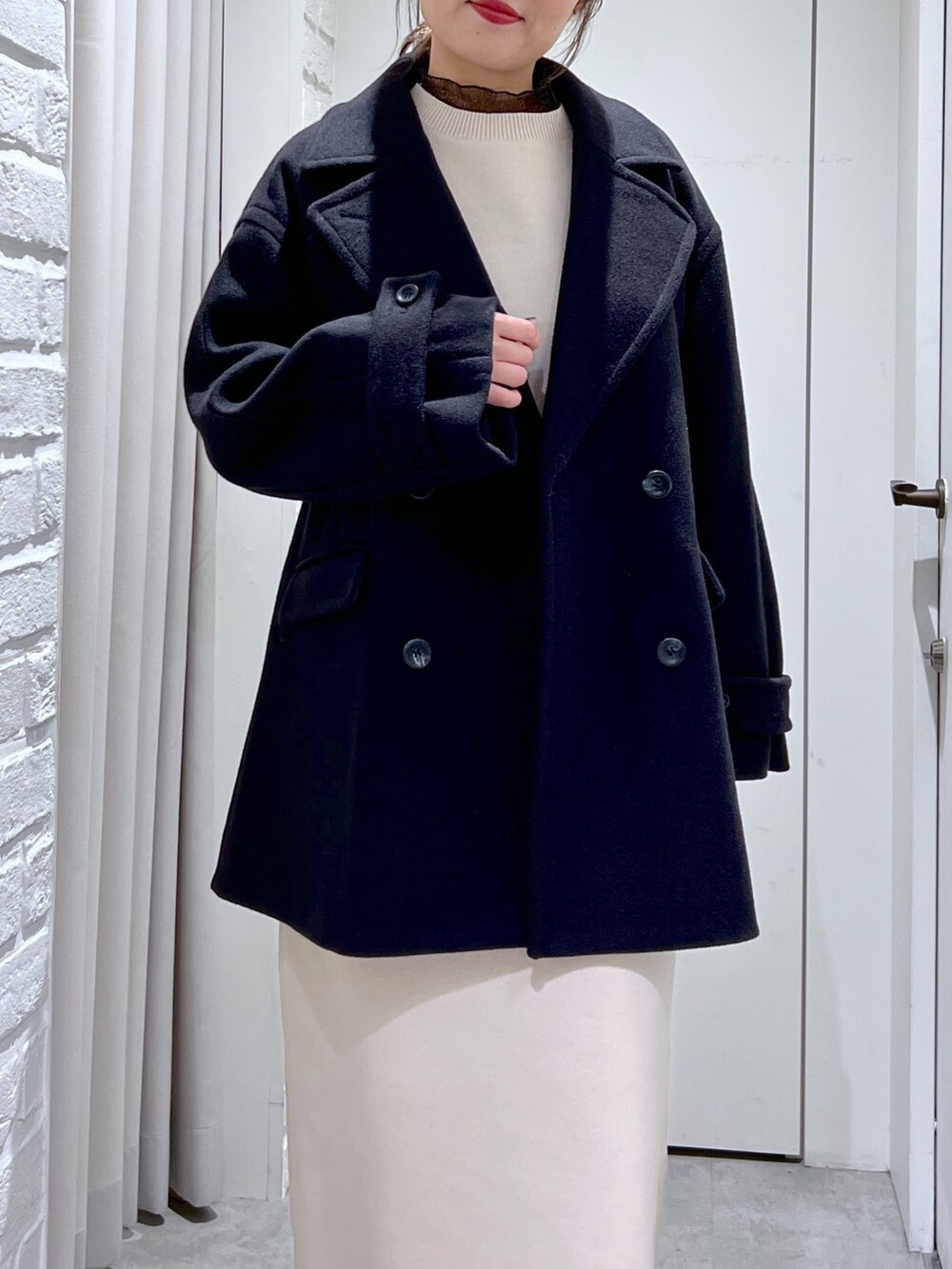 ブラック系のピーコート、ホワイト系のワンピース、ブラック系のTシャツ/カットソーを着用したレディースの冬コーディネートの6枚目の写真