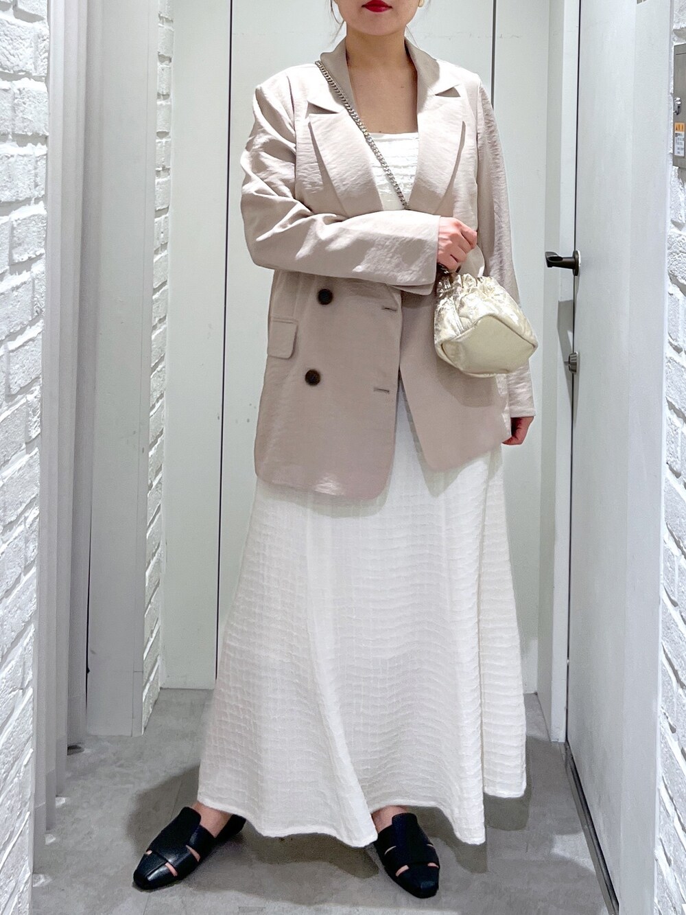 ホワイト系のワンピース、ゴールド系のショルダーバッグ、ブラック系のスリッポンを着用したレディースの春コーディネートの7枚目の写真