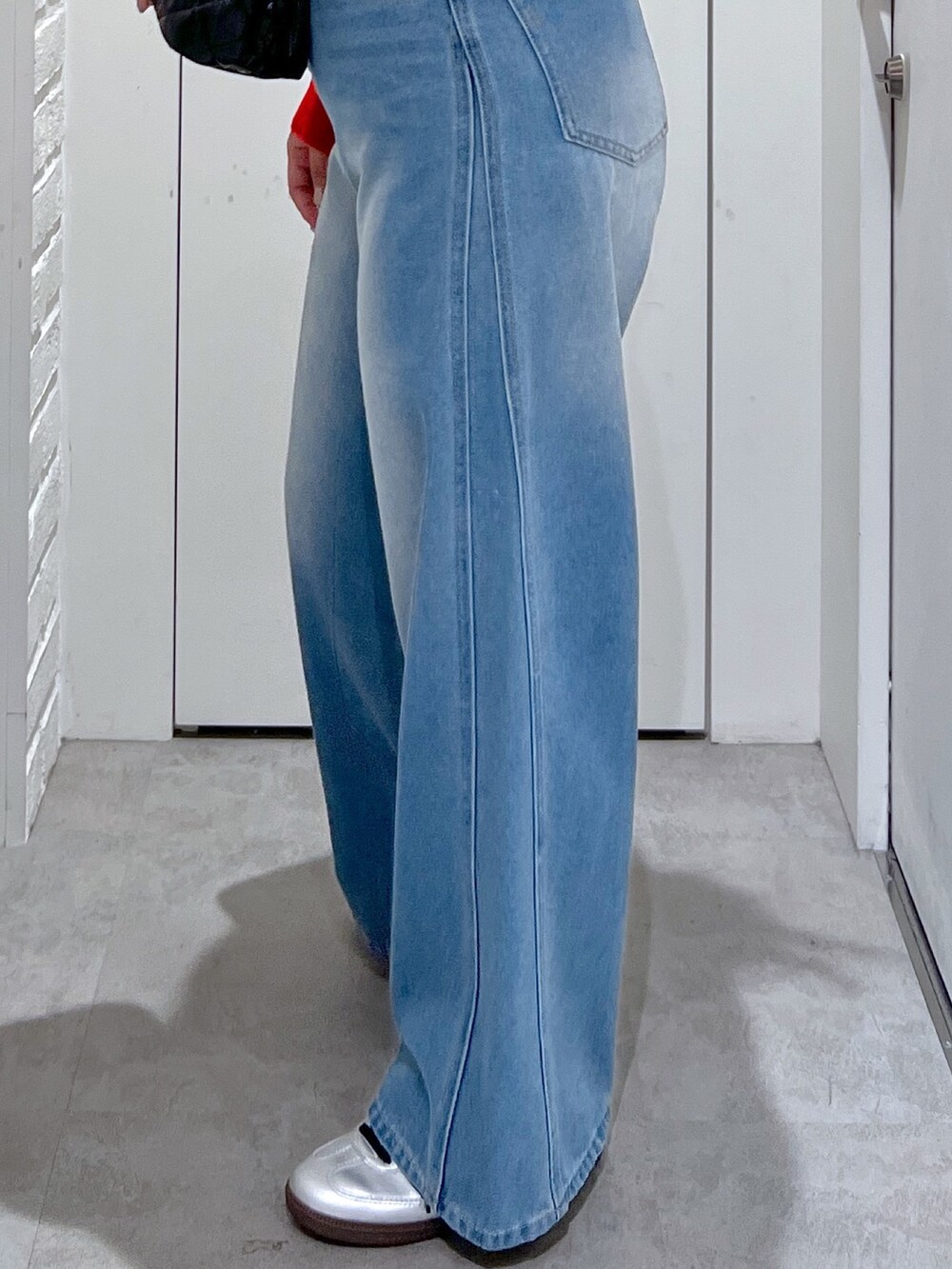 ブルー系のデニムパンツ、レッド系のカーディガン/ボレロ、ブラック系のショルダーバッグを着用したレディースの夏コーディネートの5枚目の写真