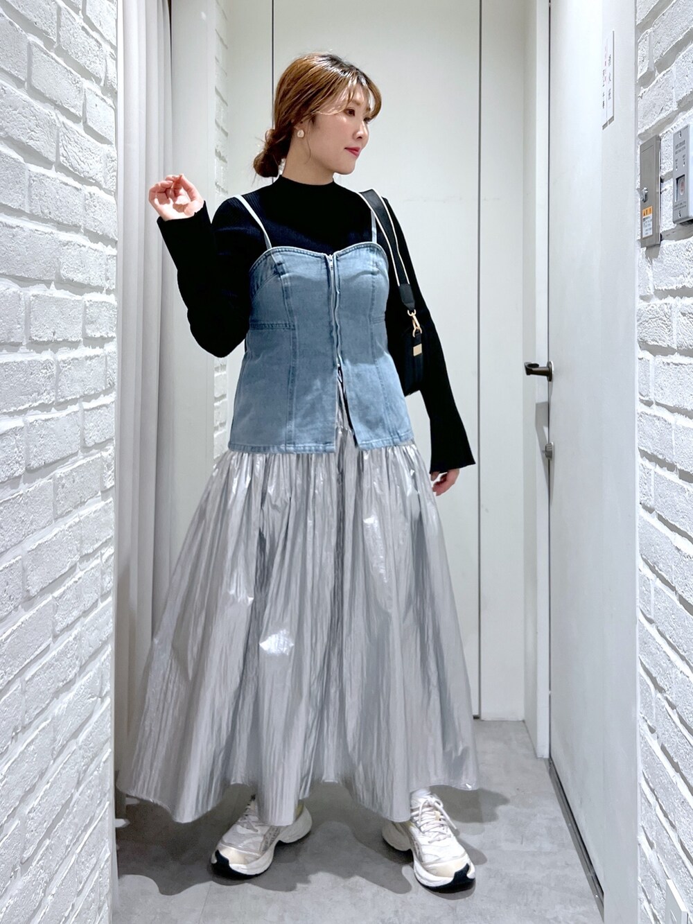 シルバー系のスカート、ブルー系のベスト、ブラック系のニット/セーターを着用したレディースの春コーディネートの2枚目の写真