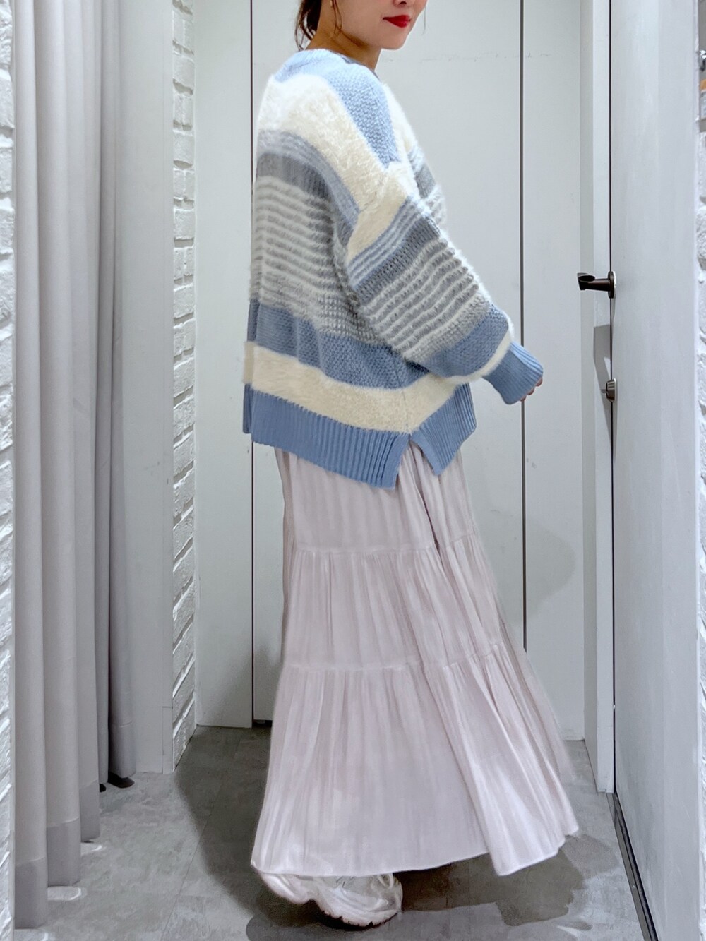 ブルー系のニット/セーター、ホワイト系のスカート、シルバー系のショルダーバッグを着用したレディースの冬コーディネートの5枚目の写真