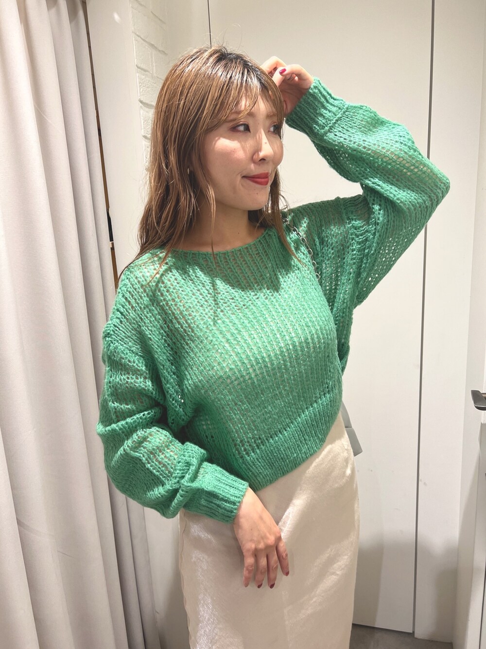 グリーン系のニット/セーター、ベージュ系のスカート、ホワイト系のブーツを着用したレディースの秋コーディネートの3枚目の写真