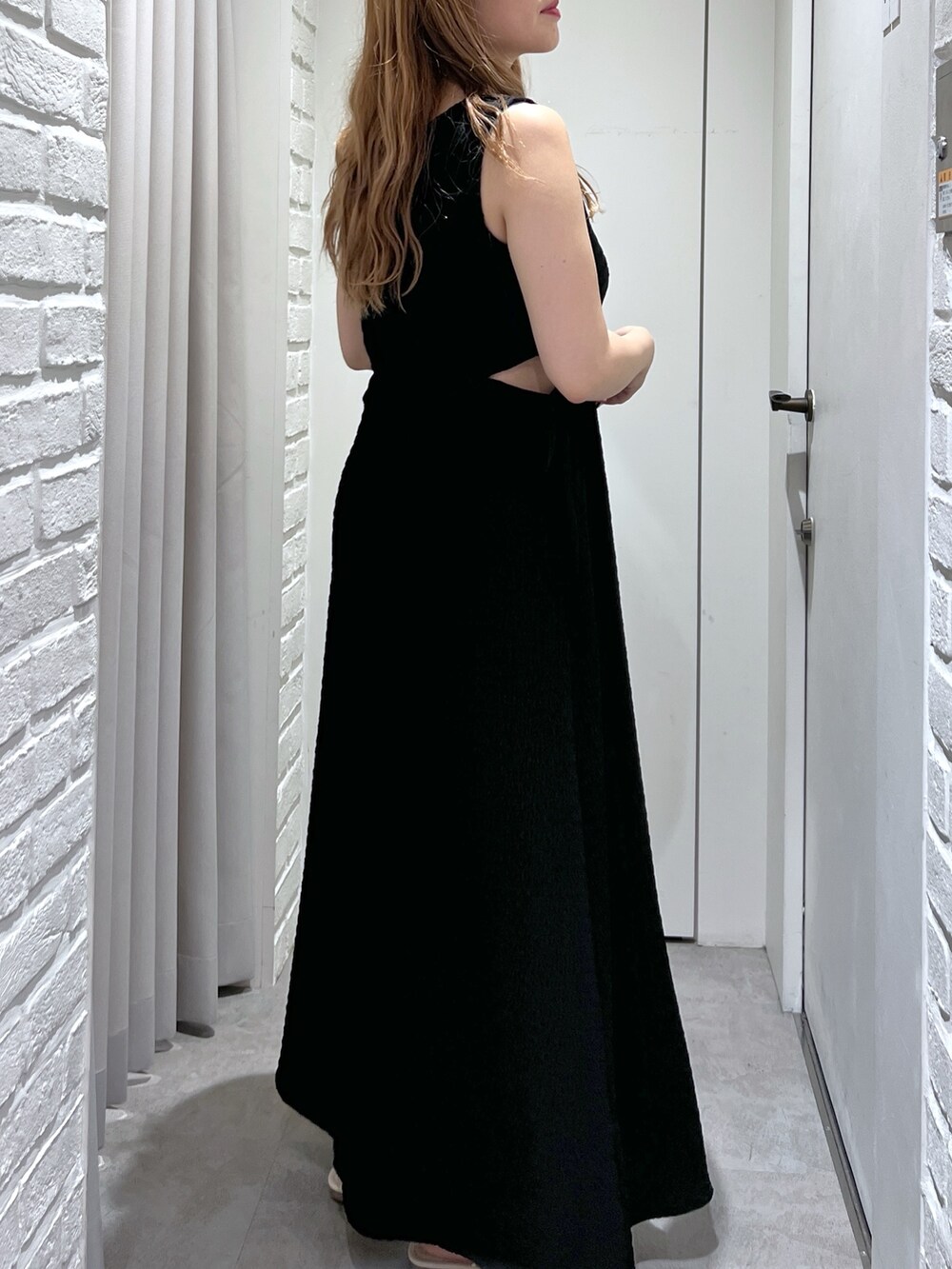 ブラック系のワンピース、ブラック系のハンドバッグ、ホワイト系のサンダルを着用したレディースの夏コーディネートの7枚目の写真