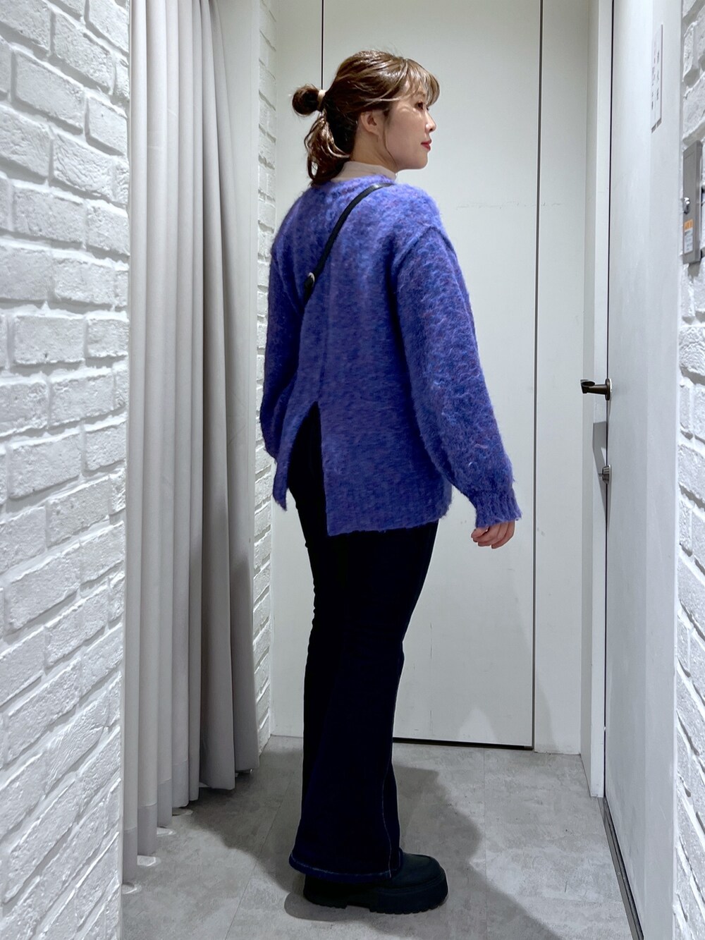 ブルー系のニット/セーター、ブルー系のデニムパンツ、ブラック系のショルダーバッグを着用したレディースの冬コーディネートの3枚目の写真