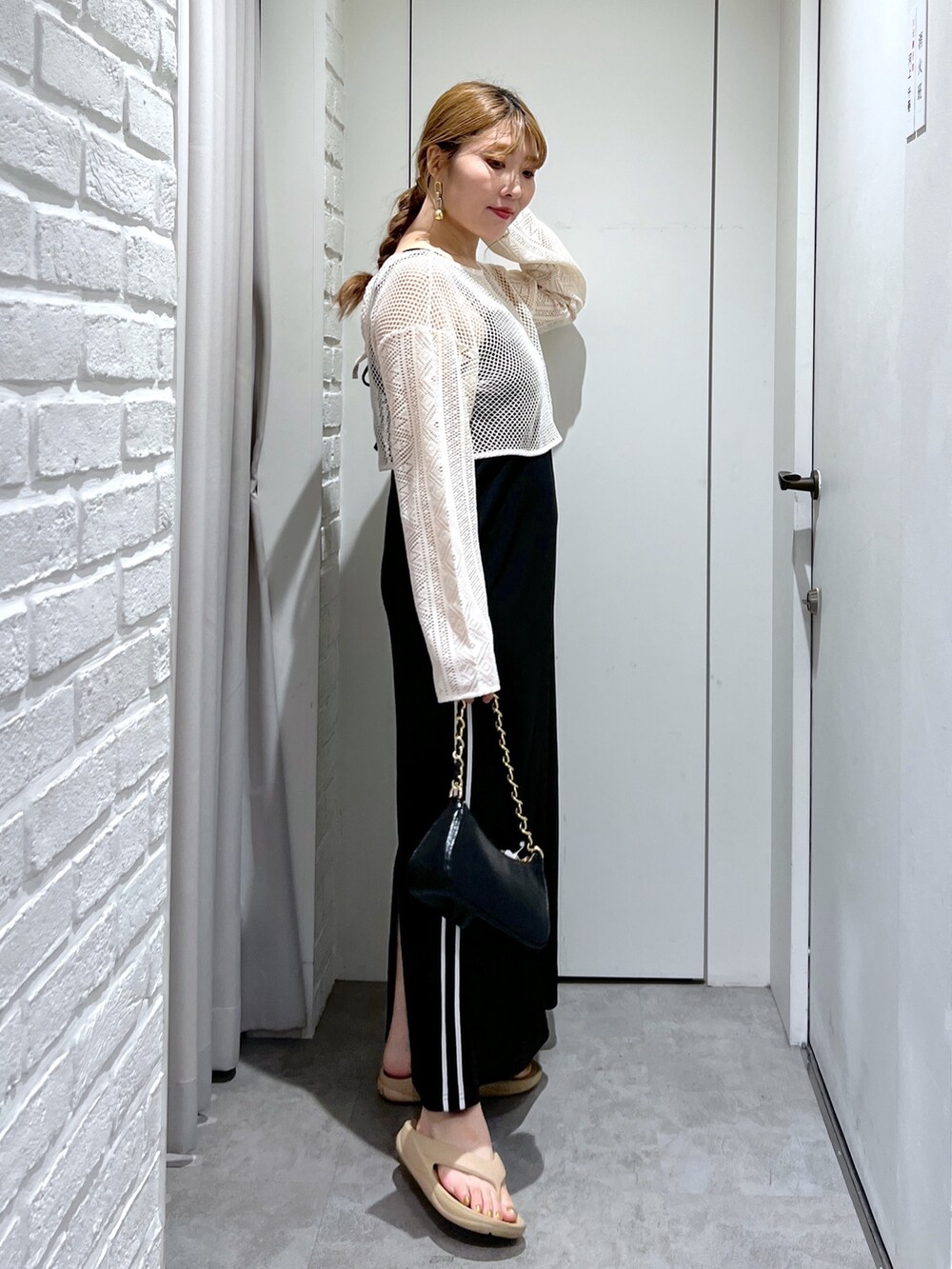 ブラック系のワンピース、ホワイト系のカーディガン/ボレロ、ブラック系のトートバッグを着用したレディースの夏コーディネートの2枚目の写真